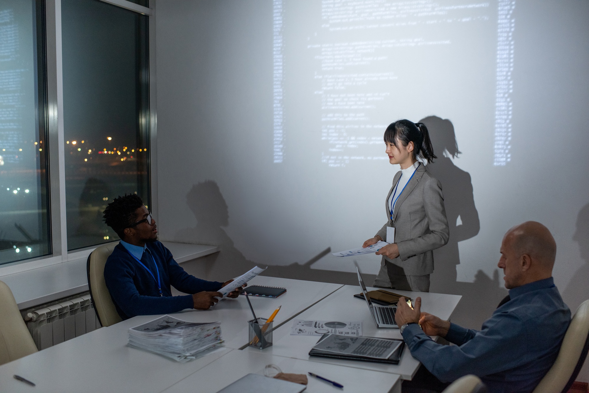 Young Asian businesswoman with papers interacting with African male colleague